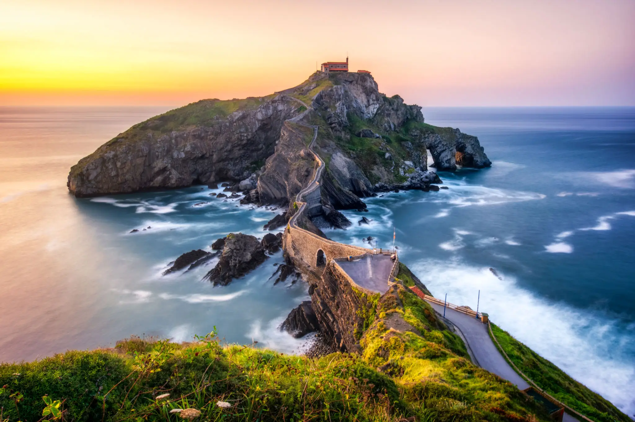 Winding stone causeway to island chapel at sunset