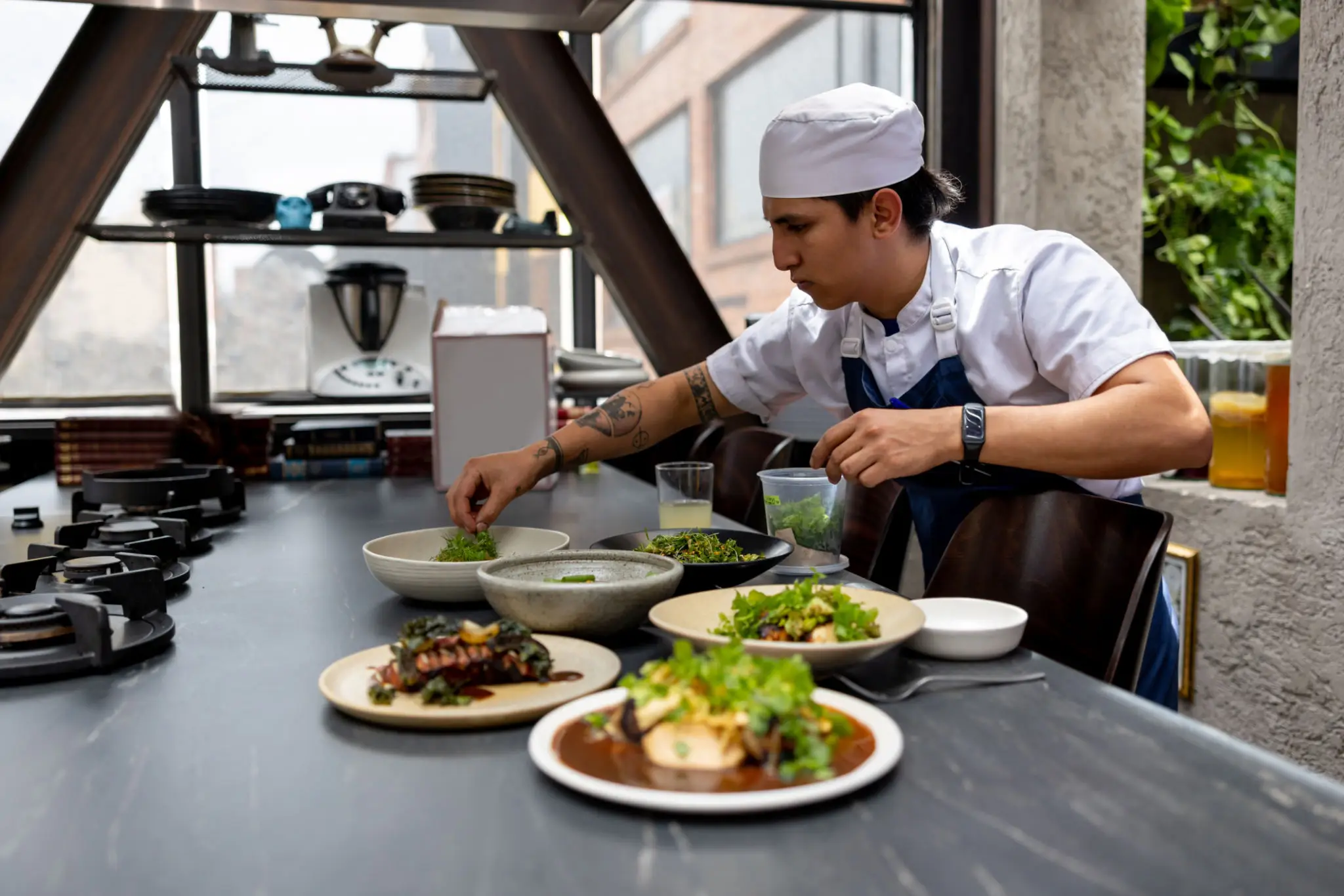 Chef garnishing plated dishes in modern kitchen