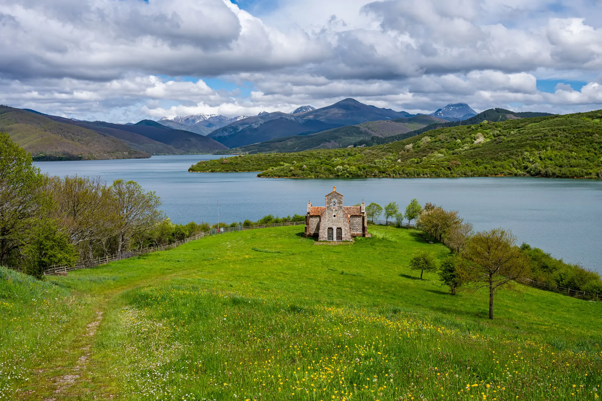 Stone chapel on green lakeside meadow