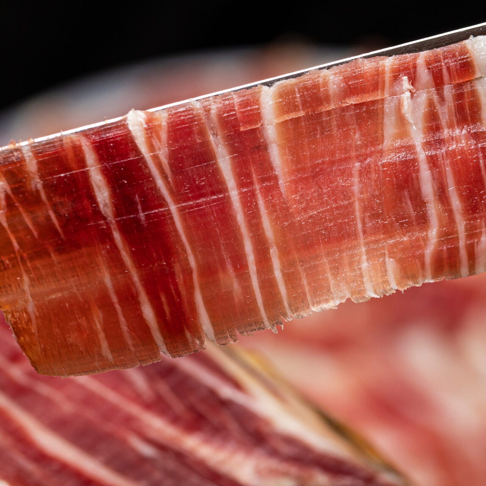 Thin slice of cured ham on knife