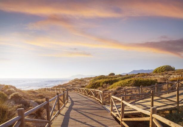Wooden boardwalk leading to sandy beach at sunset